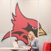A ̳ student works at a laptop in front of Cardinal mascot.
